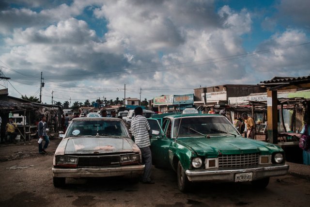 Una fila de taxis junto a la vía principal a la altura de Paraguaipoa, Venezuela. Esta localidad venezolana, el ú?ltimo punto antes de cruzar la frontera con Colombia, es desde hace años un lugar dedicado íntegramente al comercio y flujo de personas entre los dos países. Credit Santi Donaire para The New York Times en Español