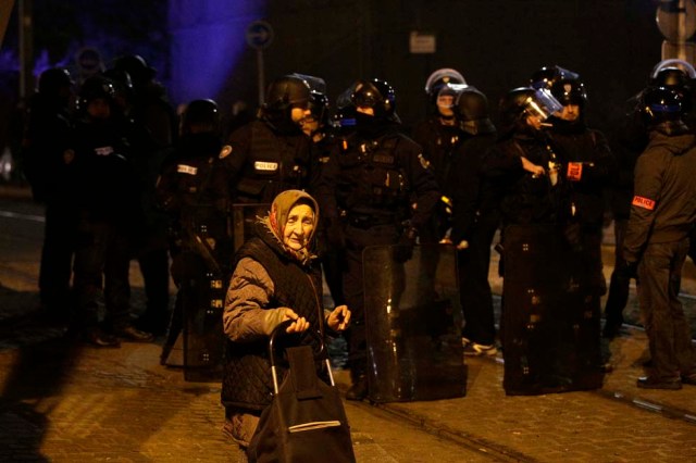 A elderly woman passes as anti riot police officers stand guard during a protest in Bobigny, a district of northeast Paris, to denounce police brutality after a black man was allegedly sodomised with a baton during an arrest while in their custody in Paris on February 11, 2017. A 22-year-old black youth worker named as Theo, a talented footballer with no criminal record, required surgery after his arrest on February 2, 2017 when he claims a police officer sodomized him with his baton. One officer has been charged with rape and three others with assault over the incident in the tough northeastern suburb of Aulnay-sous-Bois which has revived past controversies over alleged police brutality. / AFP PHOTO / GEOFFROY VAN DER HASSELT