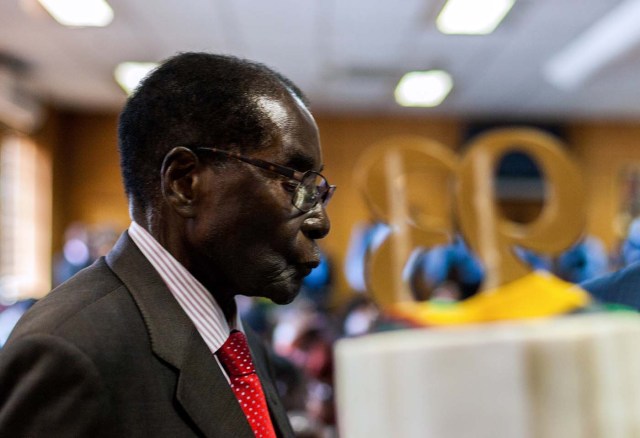 Zimbabwe's President Robert Mugabe walks past a cake bearing the number '93' on its top during a private ceremony to celebrate his 93rd birthday on February 21, 2017 in Harare.  Mugabe, the world's oldest national ruler, turned 93, using a long and occasionally rambling interview to vow to remain in power despite growing signs of frailty. / AFP PHOTO / Jekesai NJIKIZANA