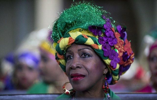 A woman dressed as "madama" attend a mass before the beginning of the Carnival in El Callao, Bolivar state, Venezuela on February 26, 2017. El Callao's carnival was recently named Unesco's Intangible Cultural Heritage of Humanity and is led by the madamas, the pillars of Callaoense identity representing Antillean matrons considered the communicators of values, who dance and wear colourful dresses. / AFP PHOTO / JUAN BARRETO