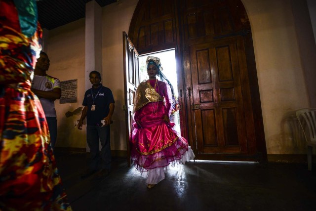 Women dressed as "madamas" attend a mass before the beginning of the Carnival in El Callao, Bolivar state, Venezuela on February 26, 2017.  El Callao's carnival was recently named Unesco's Intangible Cultural Heritage of Humanity and is led by the madamas, the pillars of Callaoense identity representing Antillean matrons considered the communicators of values, who dance and wear colourful dresses. / AFP PHOTO / JUAN BARRETO