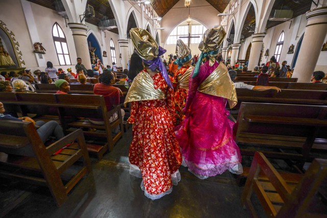 Women dressed as "madamas" attend a mass before the beginning of the Carnival in El Callao, Bolivar state, Venezuela on February 26, 2017.  El Callao's carnival was recently named Unesco's Intangible Cultural Heritage of Humanity and is led by the madamas, the pillars of Callaoense identity representing Antillean matrons considered the communicators of values, who dance and wear colourful dresses. / AFP PHOTO / JUAN BARRETO