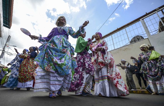 Women dressed as "madamas" dance as they take part in a parade during the Carnival in El Callao, Bolivar state, Venezuela on February 26, 2017.  El Callao's carnival was recently named Unesco's Intangible Cultural Heritage of Humanity and is led by the madamas, the pillars of Callaoense identity representing Antillean matrons considered the communicators of values, who dance and wear colourful dresses. / AFP PHOTO / JUAN BARRETO