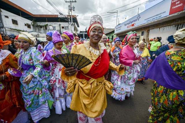 Women dressed as "madamas" dance as they take part in a parade during the Carnival in El Callao, Bolivar state, Venezuela on February 26, 2017.  El Callao's carnival was recently named Unesco's Intangible Cultural Heritage of Humanity and is led by the madamas, the pillars of Callaoense identity representing Antillean matrons considered the communicators of values, who dance and wear colourful dresses. / AFP PHOTO / JUAN BARRETO