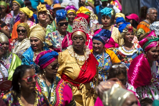 Women dressed as "madamas" dance as they take part in a parade during the Carnival in El Callao, Bolivar state, Venezuela on February 26, 2017.  El Callao's carnival was recently named Unesco's Intangible Cultural Heritage of Humanity and is led by the madamas, the pillars of Callaoense identity representing Antillean matrons considered the communicators of values, who dance and wear colourful dresses. / AFP PHOTO / JUAN BARRETO