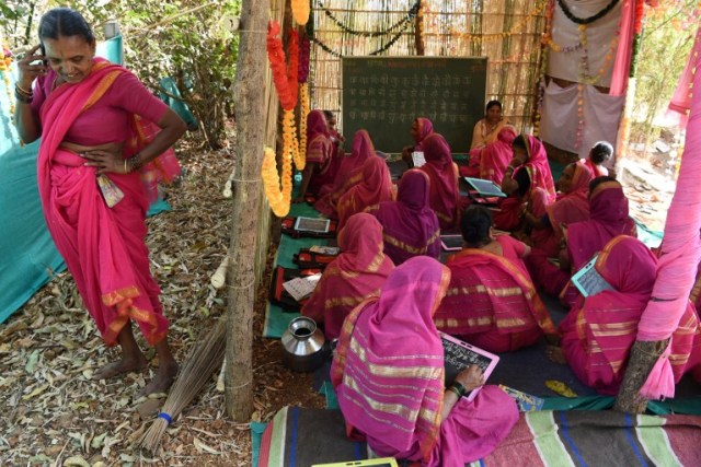 This photo taken on March 1, 2017 shows Indian grandmother Savita Deshmukh (L), 62, taking a phone call as her classmates take part in a class at Aajibaichi Shala, or "school for grannies" in the local Marathi language, in Phangane village in Maharashtra state's Thane district, some 125km northeast of Mumbai. They wear uniforms, carry satchels, and eagerly recite the alphabet in class, but the students here are different -- this is a "school for grannies". Deprived of an education as children, the women -- most of whom are widows and aged between 60 and 90 -- are finally fulfilling a life-long dream to become literate through this unique initiative near Mumbai. / AFP PHOTO / Indranil MUKHERJEE / TO GO WITH "India-education-women-school,FEATURE" by Peter HUTCHISON