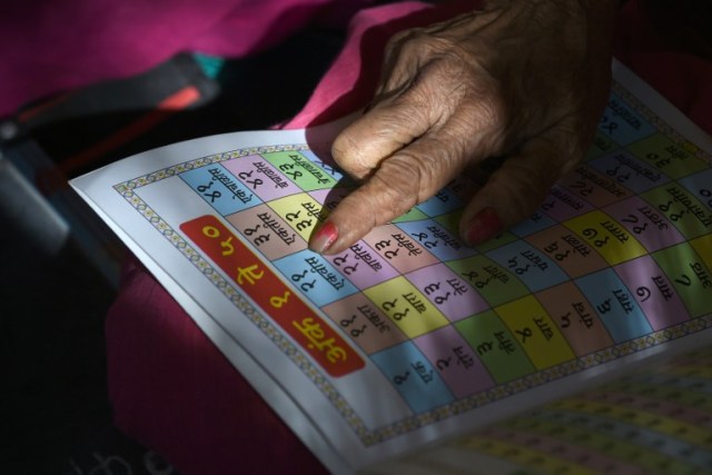 This photo taken on March 1, 2017 shows Indian grandmother Ramabai Khandakre, 69, reading from a textbook during a class at Aajibaichi Shala, or "school for grannies" in the local Marathi language, in Phangane village in Maharashtra state's Thane district, some 125km northeast of Mumbai. They wear uniforms, carry satchels, and eagerly recite the alphabet in class, but the students here are different -- this is a "school for grannies". Deprived of an education as children, the women -- most of whom are widows and aged between 60 and 90 -- are finally fulfilling a life-long dream to become literate through this unique initiative near Mumbai. / AFP PHOTO / Indranil MUKHERJEE / TO GO WITH "India-education-women-school,FEATURE" by Peter HUTCHISON