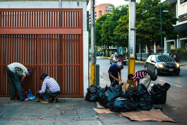 People scavenge for food in the streets of Caracas on February 22, 2017. Venezuelan President Nicolas Maduro is resisting opposition efforts to hold a vote on removing him from office. The opposition blames him for an economic crisis that has caused food shortages. / AFP PHOTO / Federico PARRA