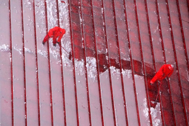 Workers clear steps in Times Square as snow falls in Manhattan, New York, U.S., March 14, 2017. REUTERS/Andrew Kelly