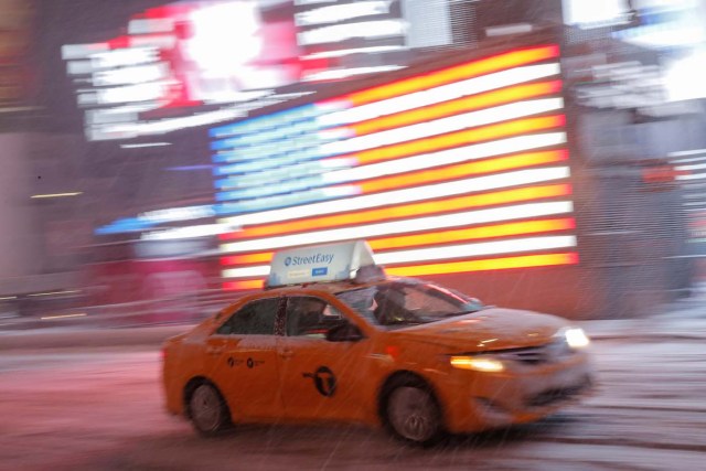 A taxi cab drives through Times Square as snow falls in Manhattan, New York, U.S., March 14, 2017. REUTERS/Andrew Kelly