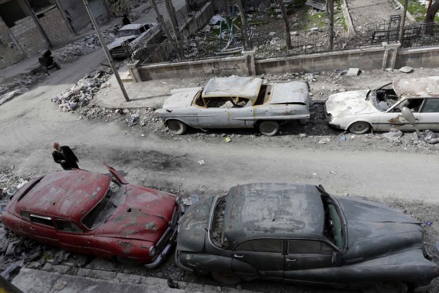 A picture taken on March 9, 2017, shows 70-year-old Mohammad Mohiedine Anis inspecting the cars parked outside his home in Aleppo's formerly rebel-held al-Shaar neighbourhood.  / AFP PHOTO / JOSEPH EID