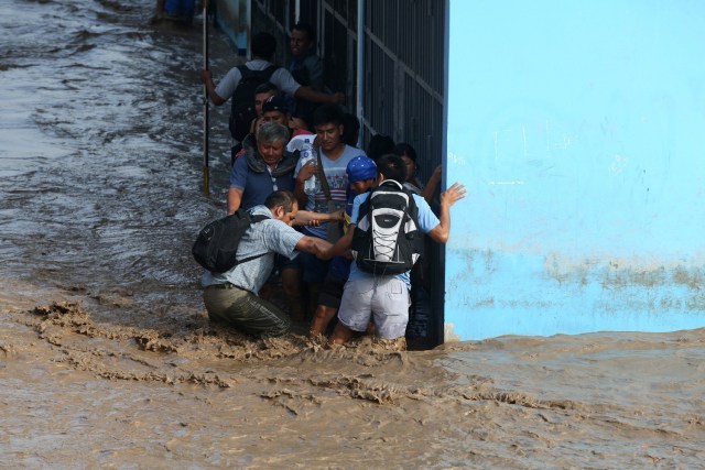 REFILE - CORRECTING NAME OF THE RIVER People help each other while standing on a flooded street after the Huaycoloro river overflooded its banks sending torrents of mud and water rushing through the streets in Huachipa, Peru, March 17, 2017. REUTERS/Guadalupe Pardo