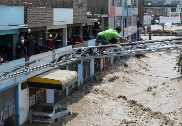 REFILE - CORRECTING NAME OF THE RIVER A man uses an extension ladder to cross a flooded street after the Huaycoloro river overflooded its banks sending torrents of mud and water rushing through the streets in Huachipa, Peru, March 17, 2017. REUTERS/Guadalupe Pardo