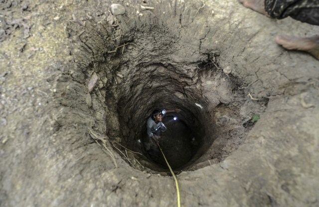 A worker descends into an underground gold mine on the bank of a river in El Callao, Bolivar state, southeastern Venezuela on February 24, 2017. Although life in the mines of eastern Venezuela is hard and dangerous, tens of thousands from all over the country head for the mines daily in overcrowded trucks, pushed by the rise in gold prices and by the severe economic crisis affecting the country, aggravated recently by the drop in oil prices. / AFP PHOTO / JUAN BARRETO