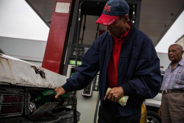 CAR303. CARACAS (VENEZUELA), 24/03/2017.- Un hombre llena el tanque de combustible de un vehículo hoy, viernes 24 de marzo de 2017, en una estación de gasolinaen Caracas (Venezuela). Decenas de estaciones de servicio en Venezuela amanecieron hoy con vehículos en cola para abastecerse de gasolina, luego de que la estatal Pdvsa reportara el pasado miércoles un retraso en el transporte de combustible y se registrasen fallos de suministro en al menos cuatro estados centrales. EFE/CRISTIAN HERNÁNDEZ