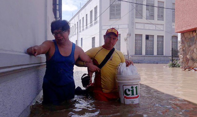 Residents in the city of Piura, 1,000 kilometres north of Lima, wade through water on the streets on March 27, 2017, after nearly 15 hours of rain caused the Piura River to overflow, flooding neighbourhoods in most of the city.  The El Nino climate phenomenon is causing muddy flash floods and rivers to overflow along the entire Peruvian coast, isolating communities and neighborhoods. Most cities face water shortages as water lines have been compromised by mud and debris. / AFP PHOTO / PATRICIA LACHIRA / BEST QUALITY AVAILABLE