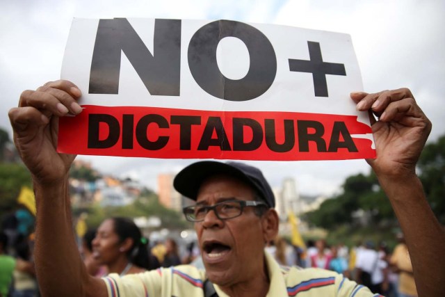 An opposition supporter holding a placard that reads, "No more dictatorship" shouts slogans as he blocks a highway during a protest against Venezuelan President Nicolas Maduro's government in Caracas, Venezuela March 31, 2017. REUTERS/Carlos Garcia Rawlins