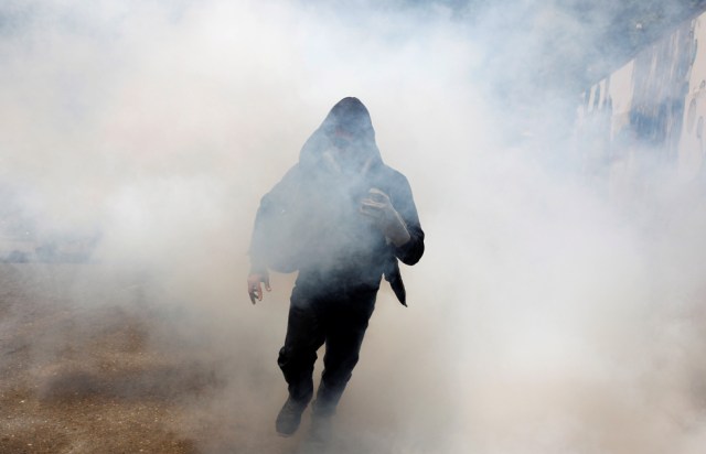 A demonstrator moves away from tear gas as riot police clashes with opposition suporters during a rally in Caracas, Venezuela, April 8, 2017. REUTERS/Carlos Garcia Rawlins