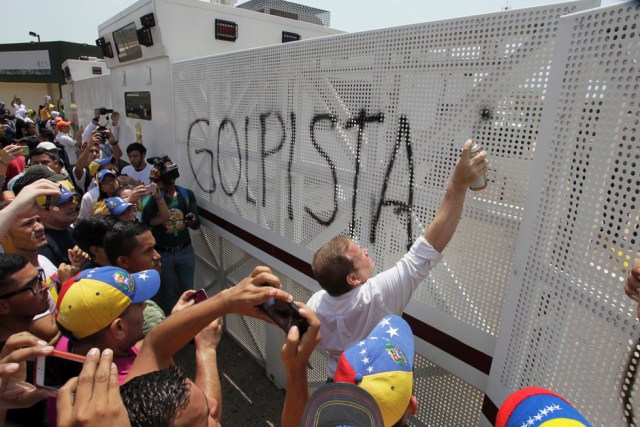 A man spray paints a graffiti that reads "coup" on an anti-riot barricade during a rally against Venezuela's President Nicolas Maduro's government in Maracaibo, Venezuela April 8, 2017. REUTERS/Isaac Urrutia FOR EDITORIAL USE ONLY. NO RESALES. NO ARCHIVES. TPX IMAGES OF THE DAY