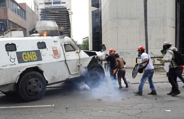 A Venezuelan National Guard riot control vehicle runs over an opposition demonstrator during a protest against Venezuelan President Nicolas Maduro, in Caracas on May 3, 2017. Venezuela's angry opposition rallied Wednesday vowing huge street protests against President Nicolas Maduro's plan to rewrite the constitution and accusing him of dodging elections to cling to power despite deadly unrest. / AFP PHOTO / FEDERICO PARRA / GRAPHIC CONTENT