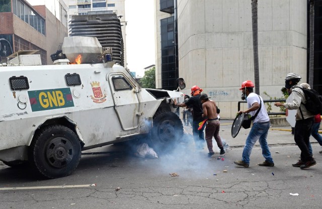 A Venezuelan National Guard riot control vehicle runs over an opposition demonstrator during a protest against Venezuelan President Nicolas Maduro, in Caracas on May 3, 2017. Venezuela's angry opposition rallied Wednesday vowing huge street protests against President Nicolas Maduro's plan to rewrite the constitution and accusing him of dodging elections to cling to power despite deadly unrest. / AFP PHOTO / FEDERICO PARRA / GRAPHIC CONTENT