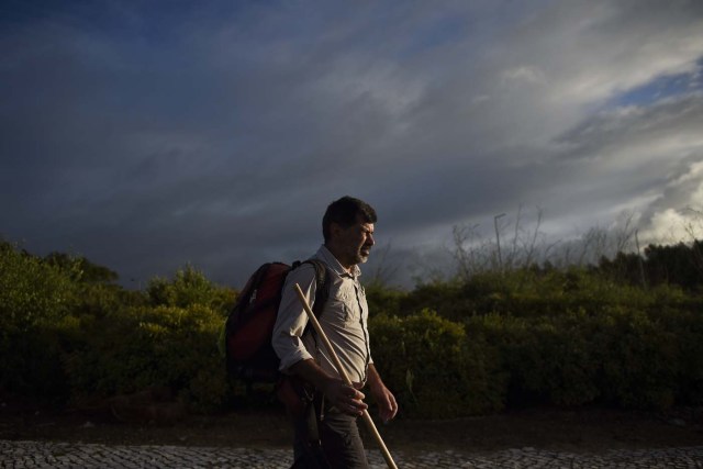 Carlos Gil starts his walk to Fatima with a backpack on his shoulders, in Cascais, outskirts of Lisbon, on May 5, 2017.  Carlos Gil is a payer-off of promises, at least that is the way the Roman Catholic refers to himself. But he is more commonly known as a rent-a-pilgrim. This 52-year-old Portuguese national takes on pilgrimages by proxy (in the name of others), especially Catholics unable to fulfil the journey because of sickness or too busy or lazy to undertake the week-long spiritual walk to the central Portuguese town of Fatima. He can be hired for an average cost of 2,500 euros. / AFP PHOTO / PATRICIA DE MELO MOREIRA / TO GO WITH AFP STORY BY BRIGITTE HAGEMANN