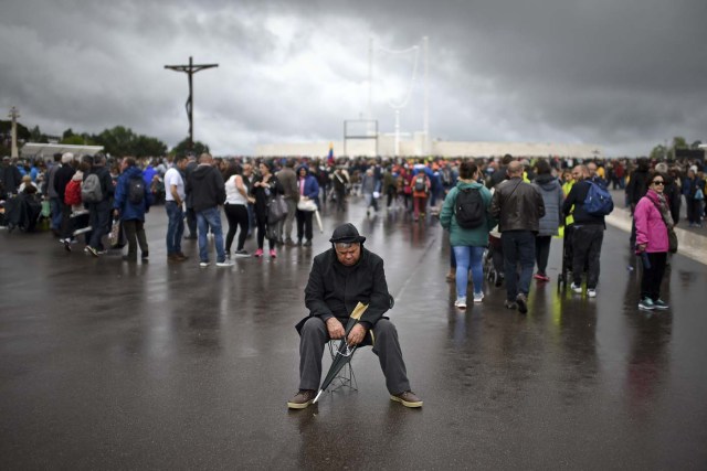 A man prays sitting on a camp stool at Fatima Sanctuary in Fatima, central Portugal, on May 12, 2017.   Two of the three child shepherds who reported apparitions of the Virgin Mary in Fatima, Portugal, one century ago, will be declared saints on May 13, 2017 by Pope Francis. The canonisation of Jacinta and Francisco Marto will take place during the Argentinian pontiff's visit to a Catholic shrine visited by millions of pilgrims every year. / AFP PHOTO / PATRICIA DE MELO MOREIRA