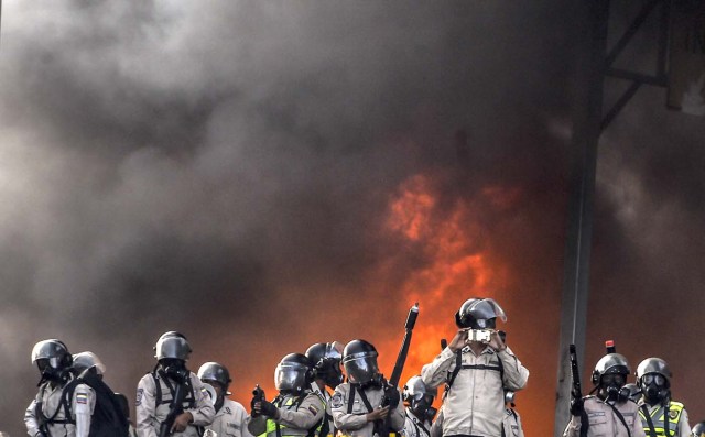 Riot police clash with anti-government protesters blocking the Francisco Fajardo highway during a demonstration against Venezuelan President Nicolas Maduro on May 27, 2017. Demonstrations that got underway in late March have claimed the lives of 58 people, as opposition leaders seek to ramp up pressure on Venezuela's leftist president, whose already-low popularity has cratered amid ongoing shortages of food and medicines, among other economic woes. / AFP PHOTO / JUAN BARRETO