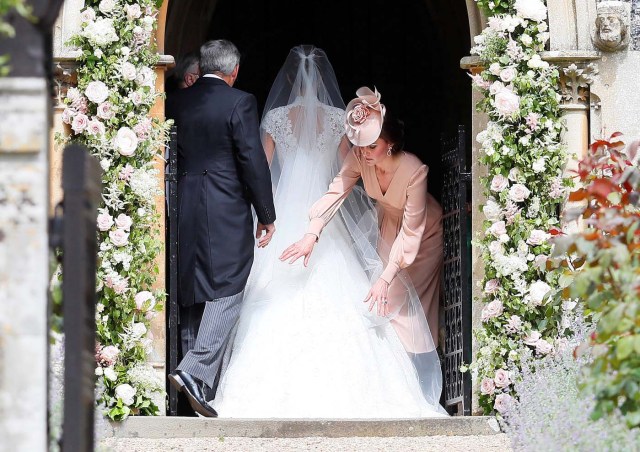 Britain's Catherine, Duchess of Cambridge (R) arranges the train of her sister Pippa Middleton as she arrives with her father Michael Middleton for her wedding to James Matthews at St Mark's Church in Englefield, west of London, on May 20, 2017. REUTERS/Kirsty Wrigglesworth/Pool