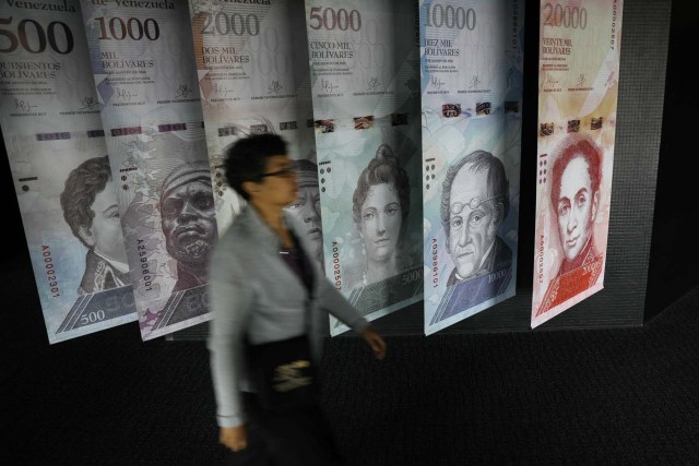 A woman walks by banners of Venezuelan bolivar notes displayed at the Venezuelan Central Bank building in Caracas, Venezuela May 23, 2017. REUTERS/Carlos Barria