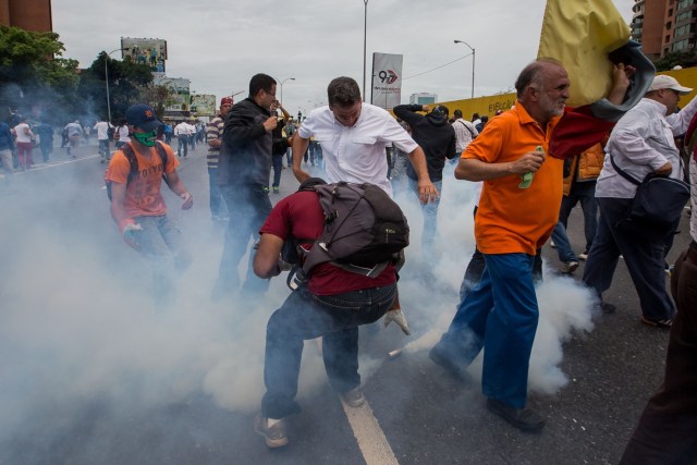 CAR007. CARACAS (VENEZUELA), 03/05/2017 - Un grupo de diputados de la Asamblea Nacional reacciona ante una bomba de gas lacrimógeno lanzada por la policía durante una mnaifestación que encabezan hoy, miércoles 3 de mayo de 2017, en Caracas (Venezuela). La Guardia Nacional Bolivariana (GNB, policía militarizada) de Venezuela dispersó hoy con gases lacrimógenos una movilización opositora en el este de Caracas que pretendía llegar hasta la sede de la Asamblea Nacional (AN, Parlamento), ubicada en el centro de la capital. EFE/MIGUEL GUTIERREZ