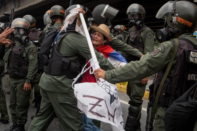 CAR013. CARACAS (VENEZUELA), 03/05/2017 - Militares retiran a una mujer que bloqueaba el paso de una tanqueta de la Guardia Nacional durante una manifestación encabezada por diputados opositores hoy, miércoles 3 de mayo de 2017, en Caracas (Venezuela). La Guardia Nacional Bolivariana (GNB, policía militarizada) de Venezuela dispersó hoy con gases lacrimógenos una movilización opositora en el este de Caracas que pretendía llegar hasta la sede de la Asamblea Nacional (AN, Parlamento), ubicada en el centro de la capital. EFE/MIGUEL GUTIERREZ