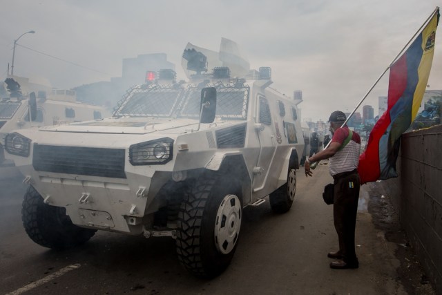 CAR019. CARACAS (VENEZUELA), 03/05/2017 - Un hombre con una bandera venezolana permanece junto a unas tanquetas de la Guardia Bolivariana durante una manifestación hoy, miércoles 3 de mayo de 2017, en Caracas (Venezuela). La Guardia Nacional Bolivariana (GNB, policía militarizada) de Venezuela dispersó hoy con gases lacrimógenos una movilización opositora en el este de Caracas que pretendía llegar hasta la sede de la Asamblea Nacional (AN, Parlamento), ubicada en el centro de la capital. EFE/MIGUEL GUTIERREZ