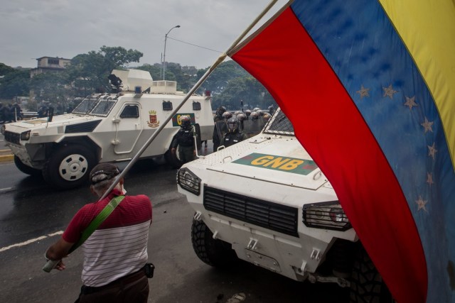 CAR020. CARACAS (VENEZUELA), 03/05/2017 - Un hombre con una bandera venezolana permanece junto a unas tanquetas de la Guardia Bolivariana durante una manifestación hoy, miércoles 3 de mayo de 2017, en Caracas (Venezuela). La Guardia Nacional Bolivariana (GNB, policía militarizada) de Venezuela dispersó hoy con gases lacrimógenos una movilización opositora en el este de Caracas que pretendía llegar hasta la sede de la Asamblea Nacional (AN, Parlamento), ubicada en el centro de la capital. EFE/MIGUEL GUTIERREZ