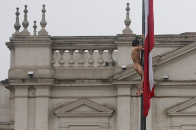 CHI02. SANTIAGO (CHILE), 25/05/2017.- Un hombre desnudo trepa el mástil de la bandera chilena en frente del Palacio de La Moneda hoy, jueves 25 de mayo de 2017, en Santiago (Chile). En una inusual protesta, de la que se desconocen hasta el momento los motivos, el hombre permaneció varios minutos en el mástil hasta que se lanzó y cayó sobre un autobús de los carabineros de la policía chilena, quienes aseguraron que el sujeto tiene problemas mentales. EFE/Marcelo Rodríguez