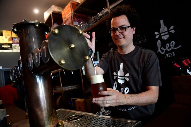 El venezolano Xavier Losada, de 36 años, trabaja en su bar "Bee Beer" en Madrid el 24 de mayo de 2017. En septiembre de 2015, Losada se trasladó con su familia a España y abrió un bar de cerveza y queso artesanal con su esposa en el centro de Madrid. Miles de venezolanos han abandonado su país para escapar de las dificultades y la violencia de su crisis económica y política. De Brasil a Estados Unidos a Europa, aquí hay cinco caras y voces de estos venezolanos que se han exiliado en los últimos dos años. / AFP FOTO / PIERRE-PHILIPPE MARCOU / PARA IR CON LA HISTORIA AFP "Los venezolanos en el exilio: cinco caras de la crisis"