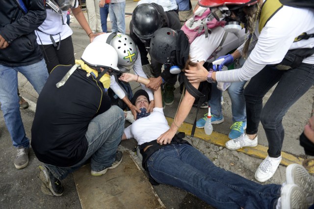 Opposition demonstrators assist an injured fellow activist during the "Towards Victory" protest against the government of President Nicolas Maduro in Caracas on June 10, 2017.  Clashes at near daily protests by demonstrators calling for Maduro to quit have left 66 people dead since April 1, prosecutors say.  / AFP PHOTO / FEDERICO PARRA