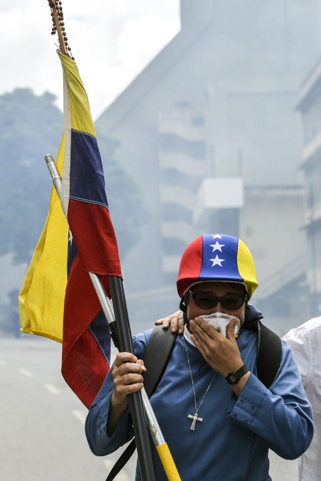 An opposition demonstrator is affected by tear gas in clashes with the riot police during the "Towards Victory" protest against the government of Nicolas Maduro, in Caracas on June 10, 2017.  Clashes at near daily protests by demonstrators calling for Maduro to quit have left 66 people dead since April 1, prosecutors say.  / AFP PHOTO / LUIS ROBAYO