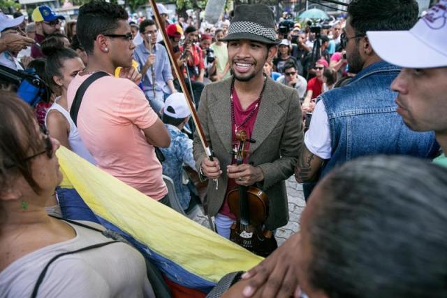 El violinista Wuilly Arteaga (c), un músico que ganó popularidad en el país luego de que su instrumento terminara dañado en medio de una protesta opositora que se tornó violenta, se presenta junto a otros músicos frente a un centenar de personas hoy, domingo 4 de junio de 2017, en la Plaza Brión de Chacaíto, en Caracas (Venezuela). Decenas de venezolanos se manifestaron en Caracas a favor de la paz y en contra del Gobierno de Nicolás Maduro, mientras la coalición opositora Mesa de la Unidad Democrática (MUD) llamó a sus simpatizantes a participar mañana en un "plantón" en varias vías del país. EFE/MIGUEL GUTIÉRREZ