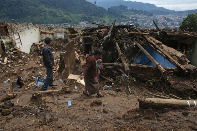 Vecinos de San Pedro Soloma, en el departamento de Huehuetenango (Guatemala), visitan hoy, jueves, 22 de junio de 2017, los restos de las viviendas soterradas luego de un derrumbe, mientras empleados gubernamentales trabajan en el área del desastre. "No nos lo esperábamos. Se oyen derrumbes en otras zonas pero no aquí". Dos días después de que un alud acabara con la vida de 12 personas en el pequeño pueblo de San Pedro Soloma, en Guatemala, la incredulidad y el estupor reinan en el ambiente. En la zona cero del desastre aún se ven las secuelas. Toneladas de tierra, piedras y escombros se amontonan sobre la carretera, en la que trabajan casi una veintena de funcionarios. Esperan dejarla libre para el sábado. EFE/Esteban Biba 