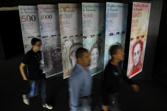 La gente camina cerca de los billetes venezolanos ampliados y exhibidos en el edificio del Banco Central de Venezuela en Caracas, Venezuela. 23 de mayo 2017. La primera subasta del nuevo sistema cambiario de Venezuela, conocido como Dicom, arrojó un tipo de cambio de 2.100 bolívares por dólar, dijo el miércoles el Banco Central. REUTERS/Carlos Barria