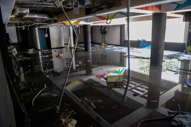 La gente busca la mercancía restante dentro de un supermercado saqueado en Maracay, estado de Aragua, Venezuela el 27 de junio de 2017. / AFP PHOTO / FEDERICO PARRA