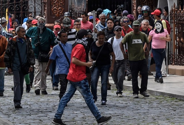 Supporters of Venezuelan President Nicolas Maduro storm the National Assembly building in Caracas on July 5, 2017 as opposition deputies hold a special session on Independence Day. A political and economic crisis in the oil-producing country has spawned often violent demonstrations by protesters demanding President Nicolas Maduro's resignation and new elections. The unrest has left 91 people dead since April 1. / AFP PHOTO / Juan BARRETO