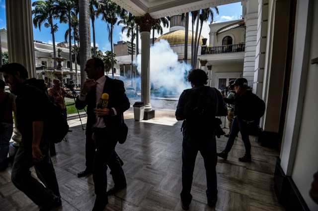 Journalists react as supporters of Venezuelan President Nicolas Maduro storm into the National Assembly building in Caracas on July 5, 2017 as opposition deputies hold a special session on Independence Day. A political and economic crisis in the oil-producing country has spawned often violent demonstrations by protesters demanding President Nicolas Maduro's resignation and new elections. The unrest has left 91 people dead since April 1. / AFP PHOTO / Juan BARRETO