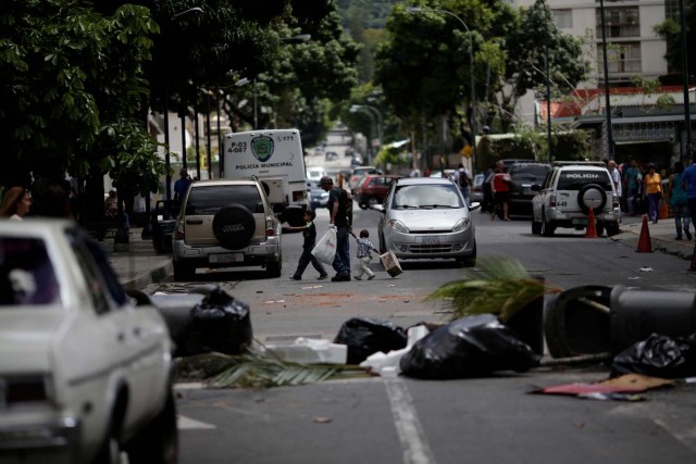 People walk through a barricade after a strike called to protest against Venezuelan President Nicolas Maduro's government in Caracas, Venezuela, July 29, 2017. REUTERS/Ueslei Marcelino