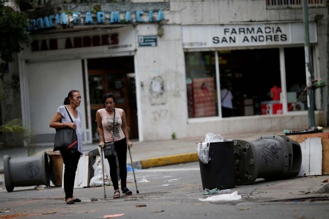 People walk through a barricade after a strike called to protest against Venezuelan President Nicolas Maduro's government in Caracas, Venezuela, July 29, 2017. REUTERS/Ueslei Marcelino