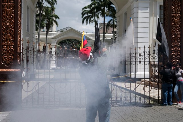 CAR16 - CARACAS (VENEZUELA), 05/07/2017 - Un simpatizante del Gobierno lanza un cohete pirotécnico hacia el edificio de la Asamblea Nacional hoy, miércoles 5 de mayo de 2017, en Caracas (Venezuela). Un grupo de simpatizantes del Gobierno venezolano irrumpió hoy por la fuerza en la Asamblea Nacional (AN, Parlamento), de mayoría opositora, y causaron heridas a algunos diputados que se encontraban en el recinto para una sesión en conmemoración del Día de la Independencia en el país. EFE/MIGUEL GUTIÉRREZ