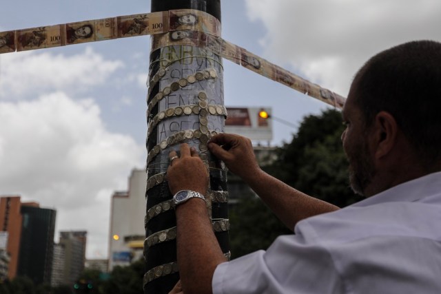 CAR114. CARACAS (VENEZUELA), 10/07/2017.- Manifestantes bloquean una vía con cintas hechas de monedas y billetes hoy, lunes 10 de julio de 2017, en Caracas (Venezuela). Los opositores venezolanos atendieron hoy a la convocatoria de realizar un "trancazo" de calles en todo el país contra la "dictadura" que se espera se extienda por diez horas, después de que la alianza antichavista intentara reducir esta protesta a solo dos horas. EFE/Miguel Gutiérrez