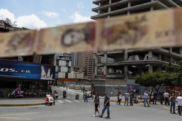 CAR116. CARACAS (VENEZUELA), 10/07/2017.- Manifestantes bloquean una vía con cintas hechas de monedas y billetes hoy, lunes 10 de julio de 2017, en Caracas (Venezuela). Los opositores venezolanos atendieron hoy a la convocatoria de realizar un "trancazo" de calles en todo el país contra la "dictadura" que se espera se extienda por diez horas, después de que la alianza antichavista intentara reducir esta protesta a solo dos horas. EFE/Miguel Gutiérrez