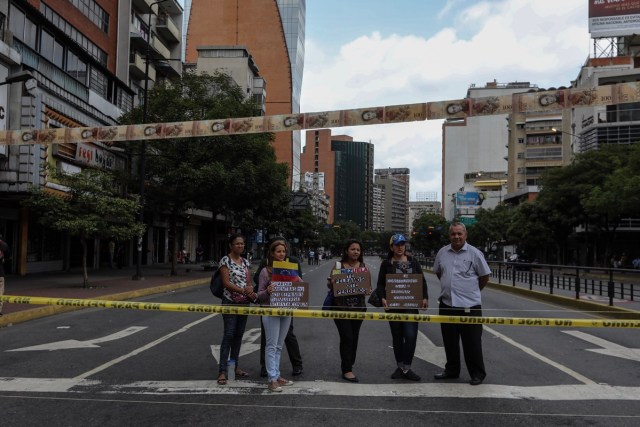 CAR119. CARACAS (VENEZUELA), 10/07/2017.- Manifestantes bloquean una vía con cintas hechas de monedas y billetes hoy, lunes 10 de julio de 2017, en Caracas (Venezuela). Los opositores venezolanos atendieron hoy a la convocatoria de realizar un "trancazo" de calles en todo el país contra la "dictadura" que se espera se extienda por diez horas, después de que la alianza antichavista intentara reducir esta protesta a solo dos horas. EFE/Miguel Gutiérrez